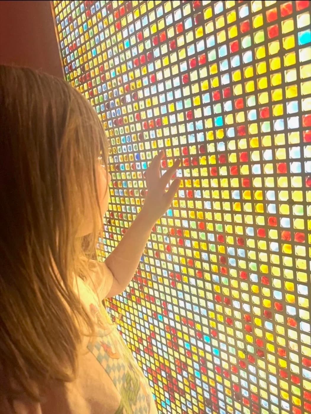 A child exploring the illuminated mosaic light wall
